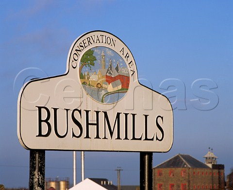 Sign at entrance to the town of Bushmills with the  Old Bushmills Whiskey Distillery in the background  County Antrim Northern Ireland