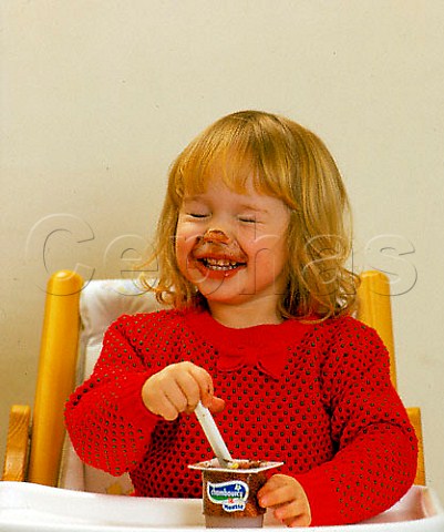 Toddler eating chocolate mousse sitting in her highchair
