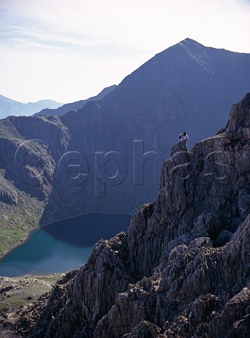 Rock climber on Crib y Ddysgl with Mount Snowdon beyond overlooking Lake Glaslyn    Snowdonia National Park Wales