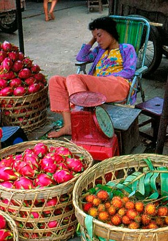 Woman selling Dragon Fruit and Rambutans in Cho Lon Market Saigon Vietnam