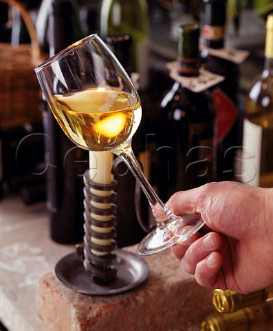 Using a candle to judge the colour and clarity of a   glass of white wine