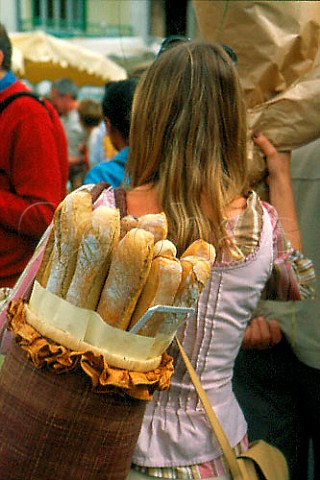Woman with basket of baguettes   in the market at IlesurlaSorgue   Vaucluse France