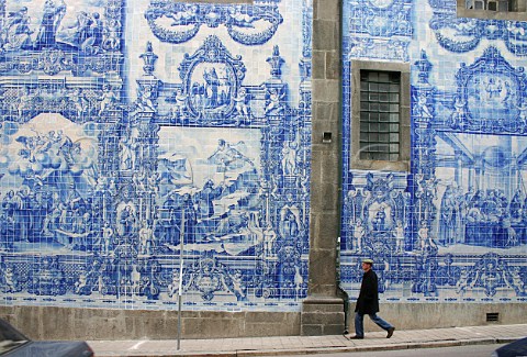 Man walks by the azulejotiled walls of Almas Chapel   in Rua de Santa Catarina Porto Portugal