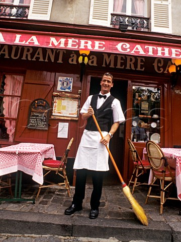 Waiter sweeping pavement outside renowned  Montmartre restaurant La Mere Catherine Paris  France