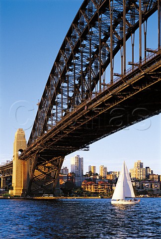 Yacht sailing under Harbour Bridge at sunset   Sydney New South Wales Australia