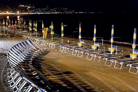 Deckchairs and paraols on Laiguglia beach at night   Liguria Italy