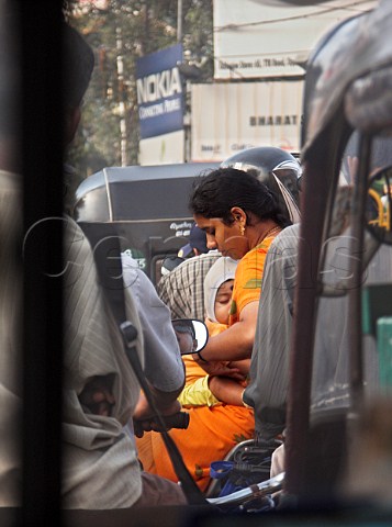 Mother and child travelling on the back of a   motorcycle in busy traffic Chennai Madras India