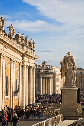 Statues on the roof of St Peters basilica overlooking the crowds visiting the Vatican in Piazza San Pietro Vatican City Rome Italy