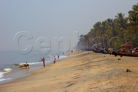 Early morning fishermen on the palm fringed beach at the rustic fishing village of Kattoor Kalavoor Alappuzha Alleppey Kerala India