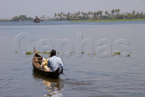 Man in canoe on one of Indias largest lakes part of the Kuttanad the backwaters of Kerala known as the Venice of the East Kerala India