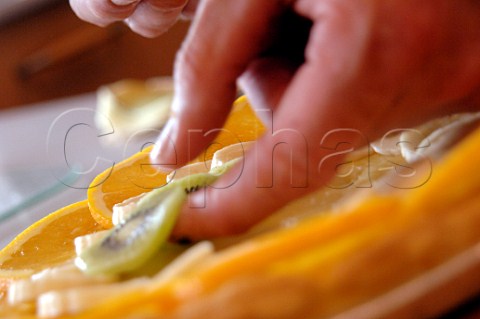 Placing fruit slices on a pastry base for a fruit tart