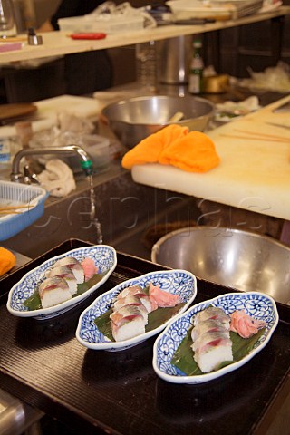 Mackerel sushi with pink ginger ready for serving in a Japanese restaurant kitchen