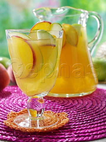 Sangria with slices of fruit on a garden table