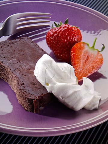 Slice of chocolate terrine with strawberries and cream