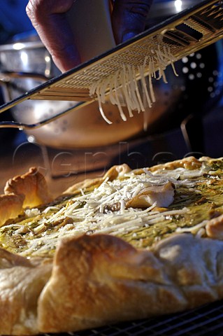 Grating parmesan cheese onto a mushroom pizza