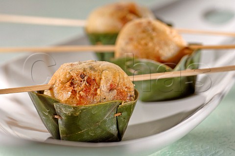Deep fried meatball in batter on kebab stick in a banana leaf container