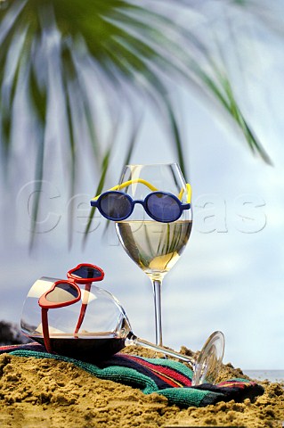 Mock beach scene with glasses of red and white wine