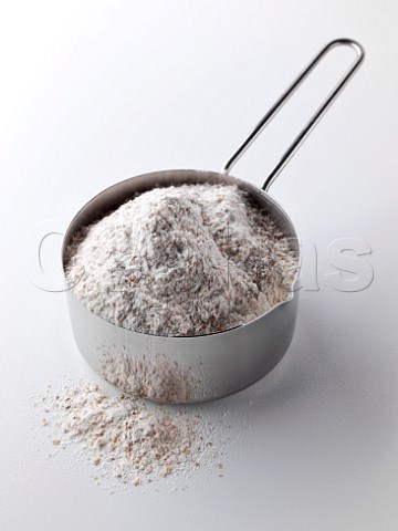 Wholemeal flour in a steel measuring cup