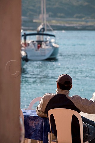 Man at caf table overlooking Favignana harbour Favignana Island Sicily Italy