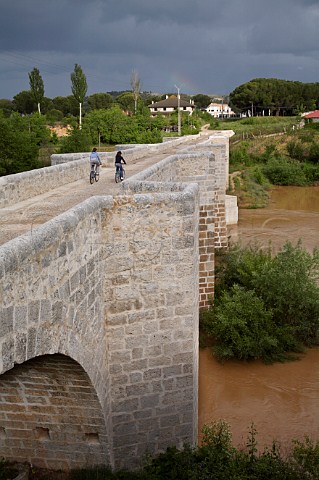 Cyclists on the old Roman bridge over the River Duero at Peafiel  Castilla y Len Spain Ribera del Duero