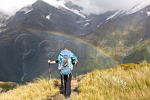 Hiker looking at rainbow on French Ridge track Mt Aspiring National Park South Island New Zealand