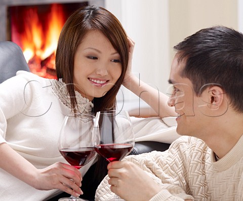 Young oriental couple drinking wine at home