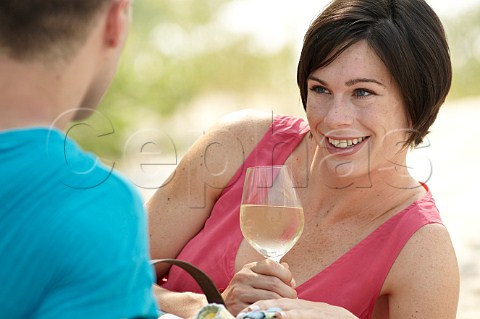 Young couple drinking wine on a beach picnic