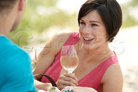 Young couple drinking wine on a beach picnic