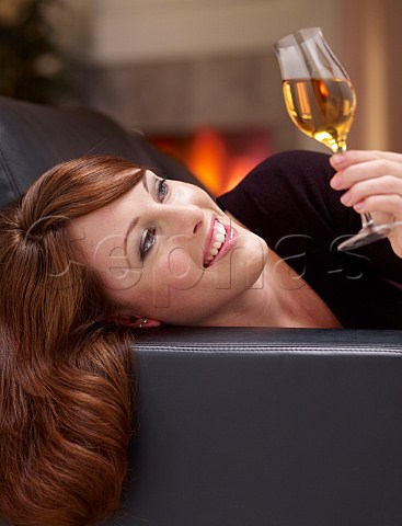 Young woman at home drinking glass of ice wine