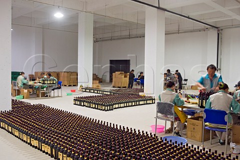 Workers gluing labels on bottles at Chateau Changyu AFIP Global winery Ju Gezhuang Beijing Miyun County China