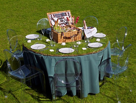 Picnic hamper on an outdoor table which has been covered with turf