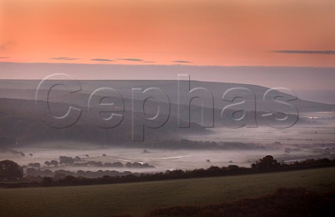 Dawn breaking over the misty Cuckmere Valley viewed from Rathfinny Wine Estate Alfriston Sussex England