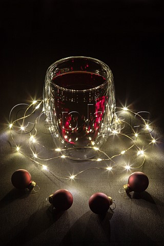Glass of mulled wine surrounded by fairy lights and Christmas baubles