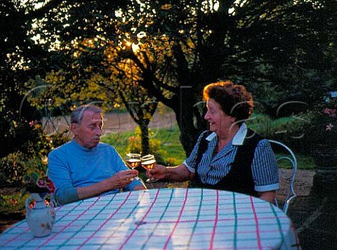 Elderly French couple enjoying a glass of rose wine   on their patio