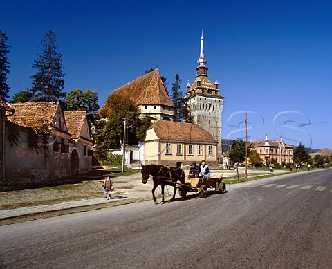 Traditional horse drawn wagon passing church at Saschiz Transylvania Romania