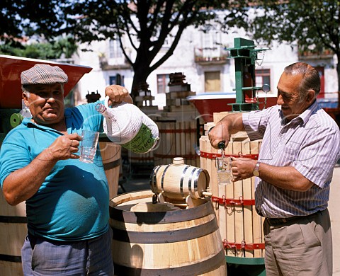 Taking a drink of Vinho Verde on a   winemaking equipment stall in the market   of Viana do Castelo Minho Portugal