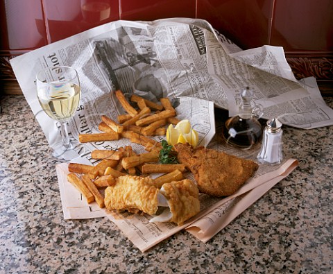 Fish and chips in newspaper with glass of white wine