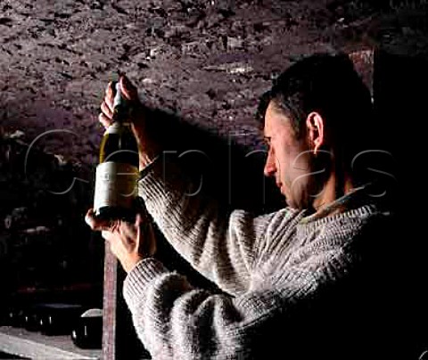 Christophe Roumier examines a bottle of   CortonCharlemagne 1990 in the cellars of   Domaine Georges Roumier ChambolleMusigny   Cte dOr France