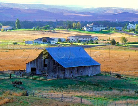 Traditional old barn alongside newer residences with   the Blue Mountains in the distance  Walla Walla Valley Washington USA