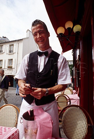 Wine waiter opening bottle at   restaurant table on the Place du Tertre   Montmartre Paris France