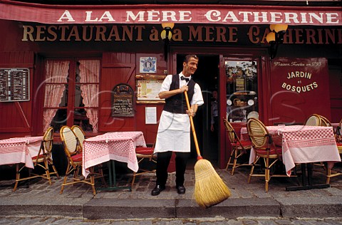 Waiter sweeping up outside restaurant A La Mere Catherine Montmartre Paris France