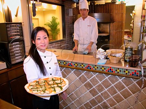 Waitress with a freshly prepared aubergine pizza in   an Italian style restaurant   Tokyo Japan