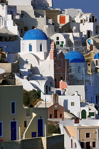 Blue domed churches amidst the houses in village of   Ia Santorini Cyclades Islands Greece