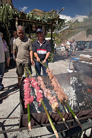 Barbequeing giant skewers of steak during a festival  at Curral das Freiras  Madeira Portugal