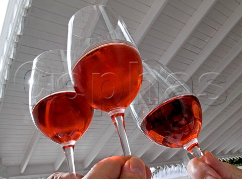 Glasses of chilled rose wine raised in a toast at an  outdoor restaurant