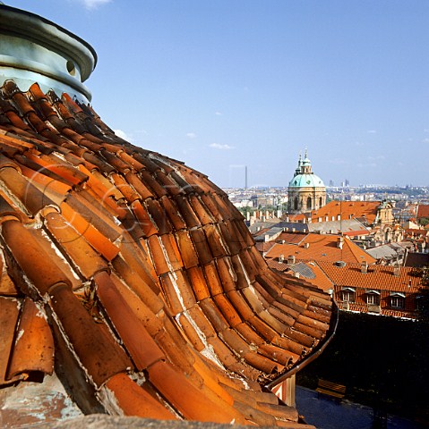 Weathered terracotta tiled roof frames view of   church and central Prague Czech Republic