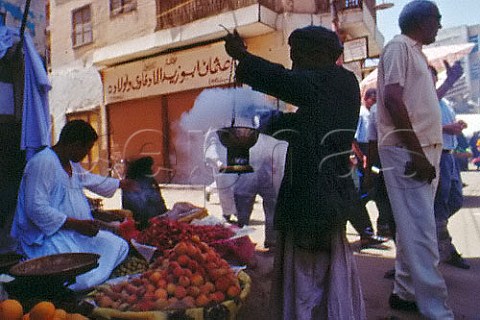 Man using incense burner for fly control   at bazaar stalls Aswan Egypt