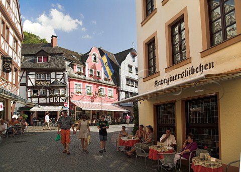 Restaurant seating in Rmerstrasser the main shopping street in Bernkastel with the Schlossberg vineyard visible on the hill above Germany Mosel