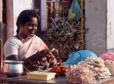 Indian woman making flower garlands For wearing in   hair during temple visit Chennai Madras India