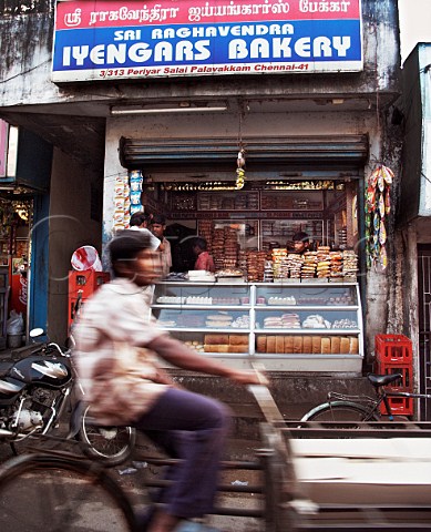 Young boy cycling past Iyengars Bakery Palavakkam   Chennai Madras India